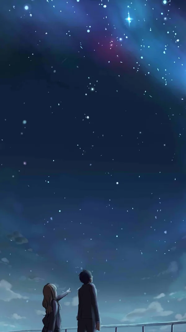 Two people standing on a bridge looking up at the night sky